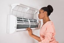 Young African Woman Checking Air Conditioner not blowing cold air